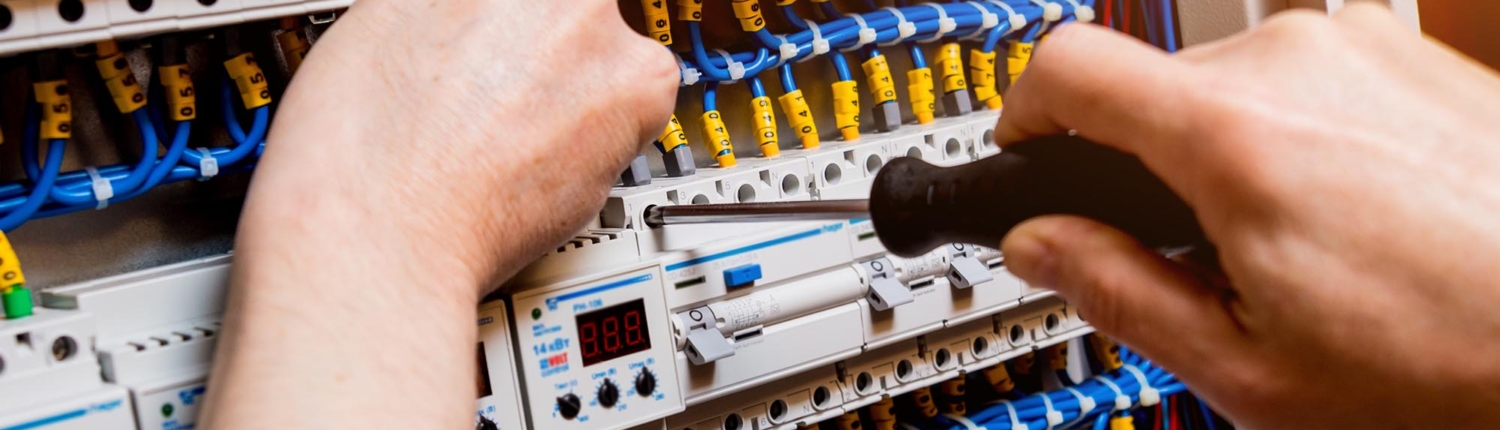 Side view of a man repairing the switchboard voltage with automatic switches