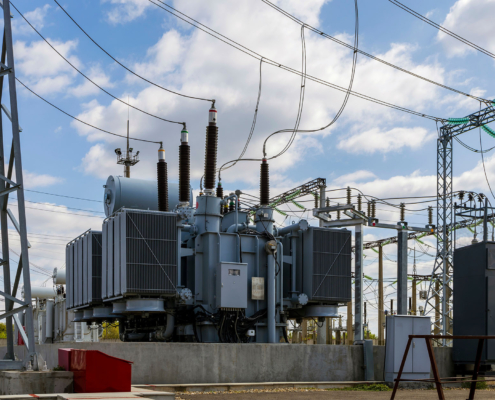 Three-phase high-voltage transformer of high electrical power at a substation against the blue sky