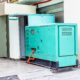 Large green industrial generator outside building